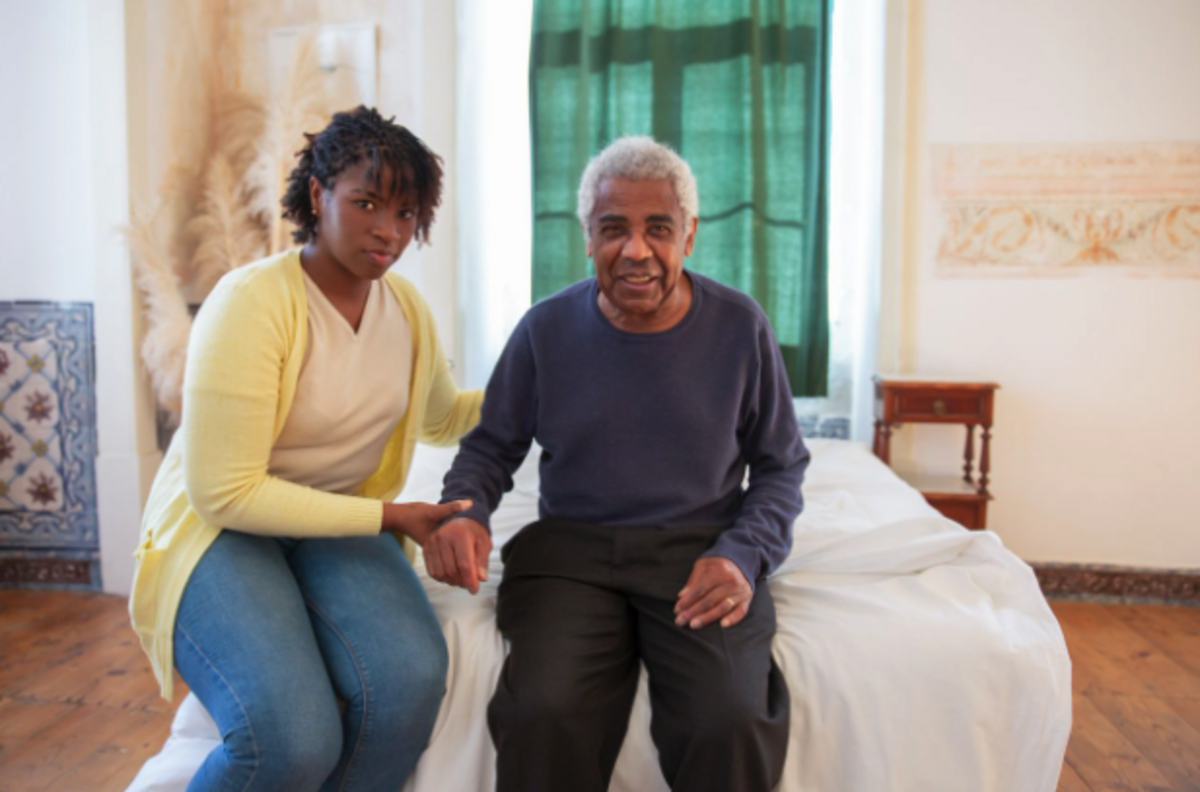 Caregiver sitting beside an older adult at home