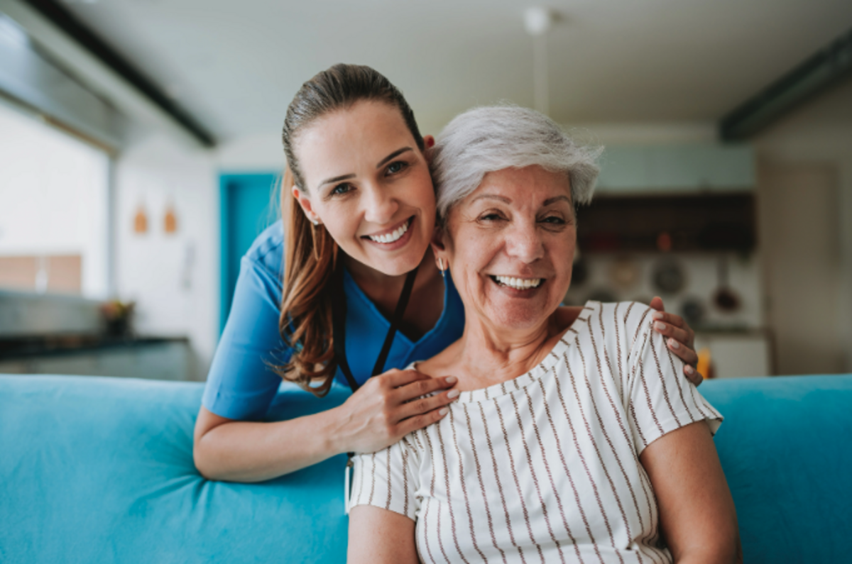 Caregiver and older adult smiling together at home